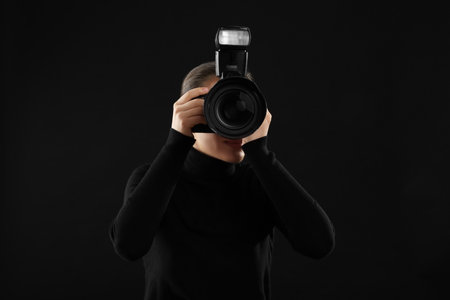 Professional photographer taking picture on black backgroundの写真素材
