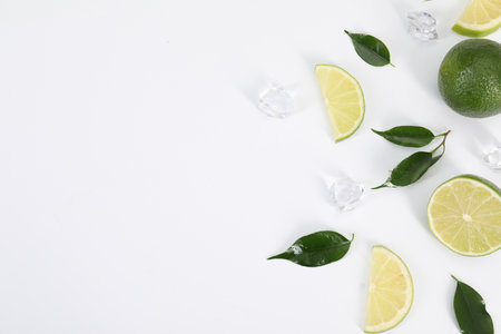 Flat lay composition with fresh limes, leaves and ice cubes on white background. Space for textの写真素材
