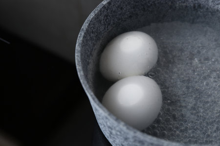 Chicken eggs boiling in saucepan on electric stove, closeupの写真素材