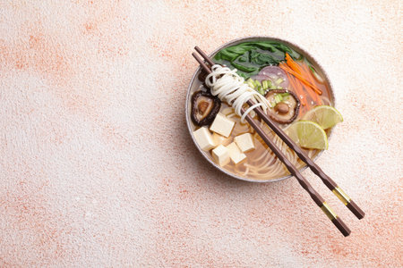 Bowl of vegetarian ramen and chopsticks on color textured table, top view. Space for textの写真素材