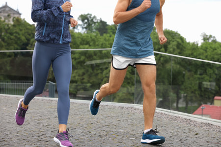 Healthy lifestyle. Sporty couple running outdoors, closeup