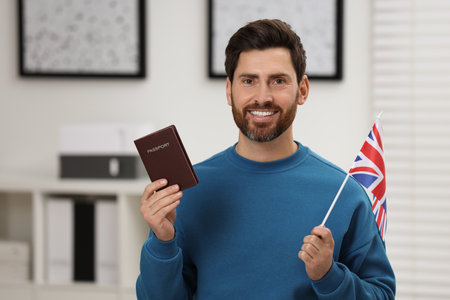 Immigration. Happy man with passport and flag of United Kingdom indoorsの写真素材