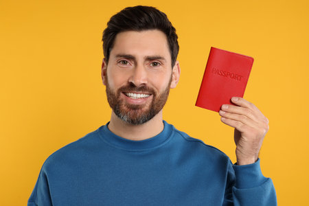 Immigration. Happy man with passport on orange backgroundの写真素材