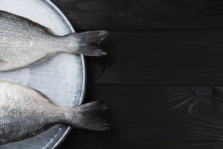 Fresh raw dorado fish on black wooden table, top view. Space for textの写真素材