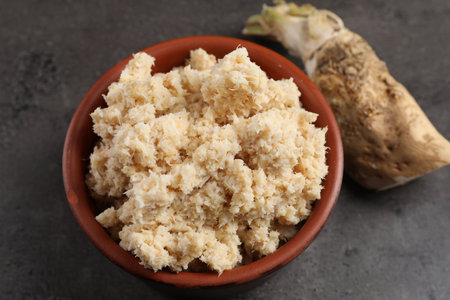 Bowl of tasty prepared horseradish and root on gray table, closeupの写真素材