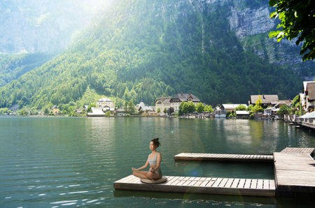 Woman meditating at riverside near beautiful mountain, space for textの写真素材