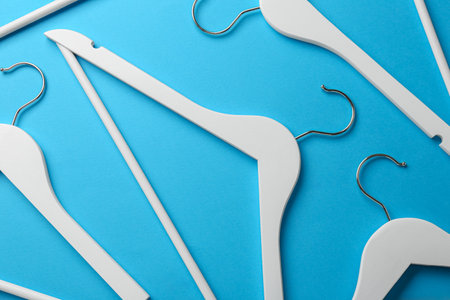 White hangers on light blue background, flat layの写真素材