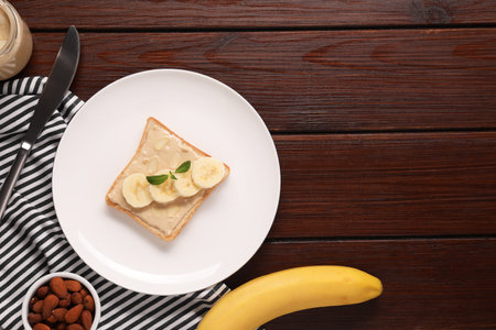 Toast with tasty nut butter, banana slices and almond flakes on wooden table, flat lay. Space for textの写真素材