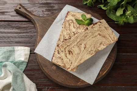 Pieces of tasty chocolate halva with mint on wooden table, top view