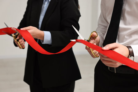 People cutting red ribbon with scissors on blurred background, closeupの写真素材