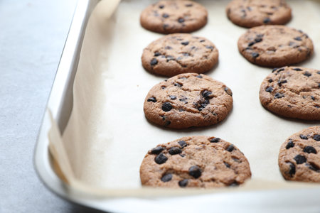 Baking pan with chocolate chip cookies on table, closeup