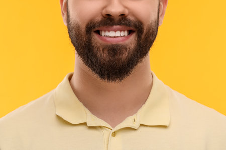 Man with clean teeth smiling on yellow background, closeupの写真素材