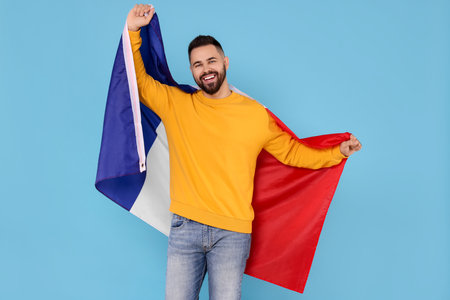 Young man holding flag of France on light blue backgroundの写真素材