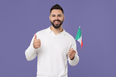 Young man with flag of Italy showing thumb up on purple backgroundの写真素材
