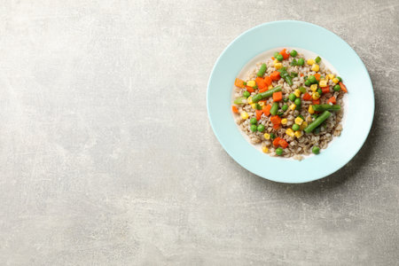 Tasty pearl barley porridge with vegetables on light textured table, top view. Space for textの写真素材