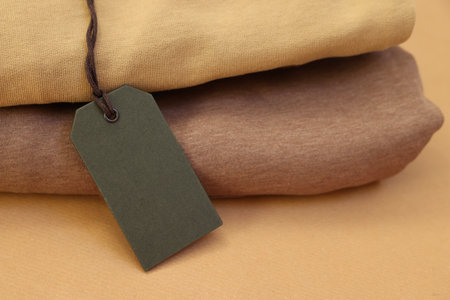 Garment with cardboard tag on kraft paper sheet, closeup. Space for textの写真素材