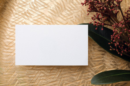 Blank business card and beautiful plant with green leaves on golden background, flat lay. Mockup for...