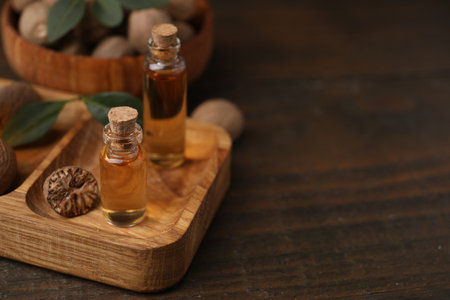 Nutmeg essential oil and nuts on wooden table. Space for textの写真素材