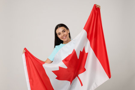 Happy young woman with flag of Canada on beige backgroundの写真素材