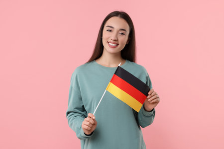 Young woman holding flag of Germany on pink backgroundの写真素材