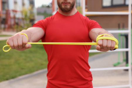 Muscular man doing exercise with elastic resistance band outdoors, closeupの写真素材