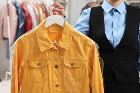 Dry-cleaning service. Woman holding shirt in plastic bag indoors, closeupの写真素材