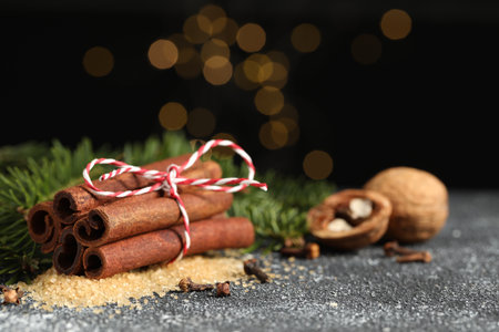 Different aromatic spices and fir branches on gray textured table, closeup. Space for text