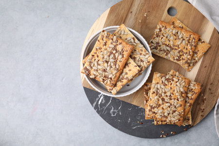 Cereal crackers with flax, sunflower and sesame seeds on gray table, top view. Space for text