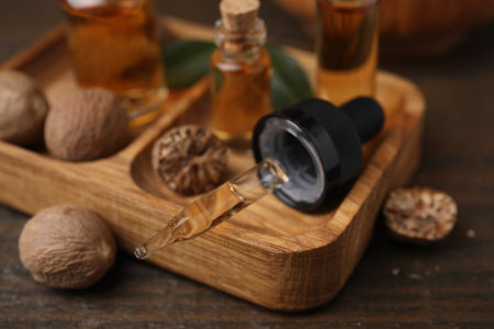 Nutmeg essential oil and nuts on wooden table, closeupの写真素材