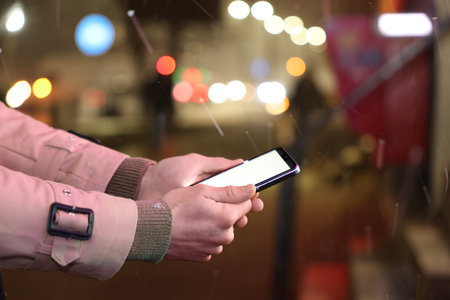 Man using smartphone on night city street, closeup. Space for text