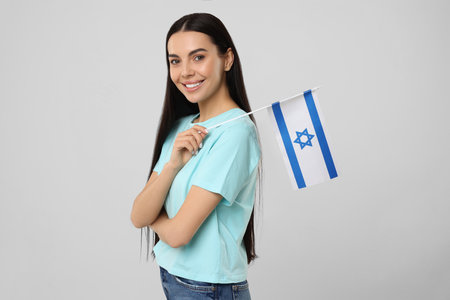 Happy young woman with flag of Israel on beige backgroundの写真素材