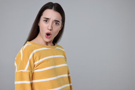 Portrait of surprised woman on gray background. Space for textの写真素材