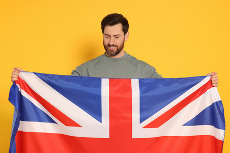 Man with flag of United Kingdom on yellow backgroundの写真素材