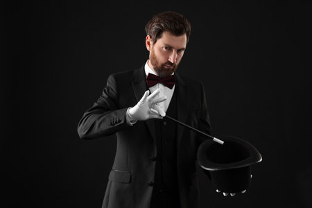 Magician showing magic trick with top hat on black backgroundの写真素材