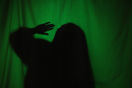 Silhouette of creepy ghost behind dark green clothの写真素材