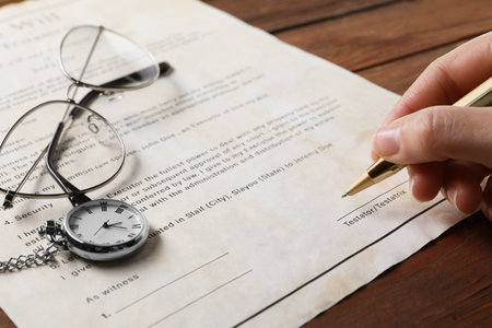 Woman signing Last Will and Testament at wooden table, closeup