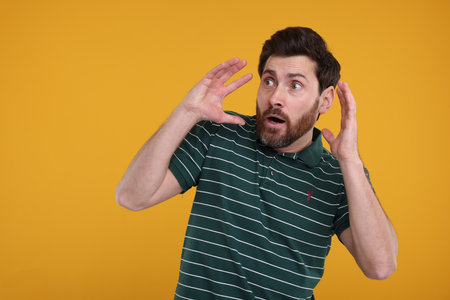 Portrait of surprised man on yellow background, space for textの写真素材