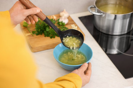 Man pouring delicious soup into bowl in kitchen, closeupの写真素材