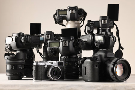 Modern cameras on white wooden table against light backgroundの写真素材