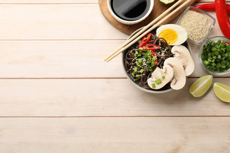Tasty buckwheat noodles (soba) with egg and mushrooms served on wooden table, flat lay. Space for...