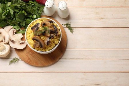 Tasty millet porridge, mushrooms and dill in bowl on light wooden table, flat lay. Space for textの写真素材