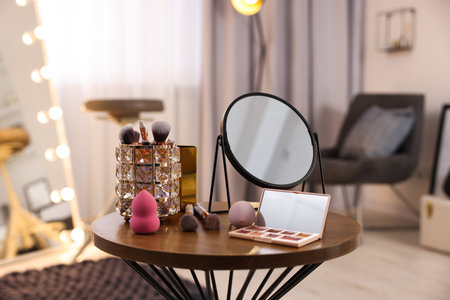Different beauty products and mirror on wooden table in makeup roomの写真素材