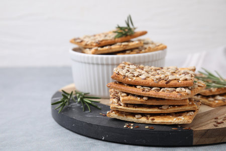 Cereal crackers with flax, sunflower, sesame seeds and rosemary on gray table, closeupの写真素材