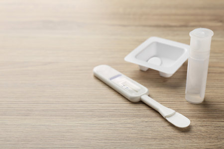 Disposable express test kit on wooden table, closeup. Space for text