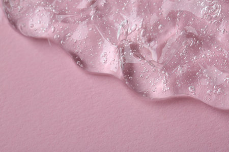 Clear cosmetic serum on pink background, macro view. Space for textの写真素材