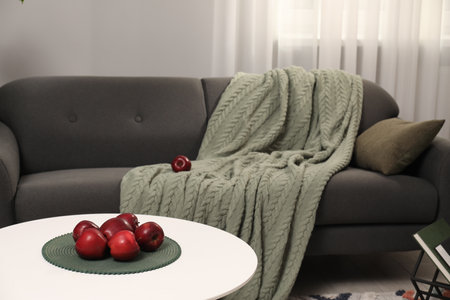 Red apples on coffee table near gray sofa with blanket indoorsの写真素材