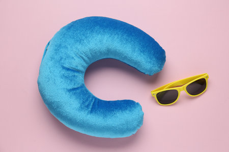 Light blue travel pillow and sunglasses on pink background, flat layの写真素材