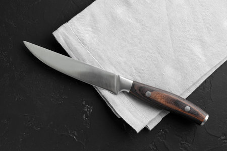 One sharp knife and napkin on dark textured table, top viewの写真素材