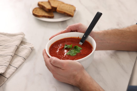 Man with delicious tomato soup at light marble table, closeupの写真素材