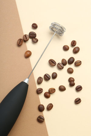 Milk frother wand and coffee beans on color background, top viewの写真素材